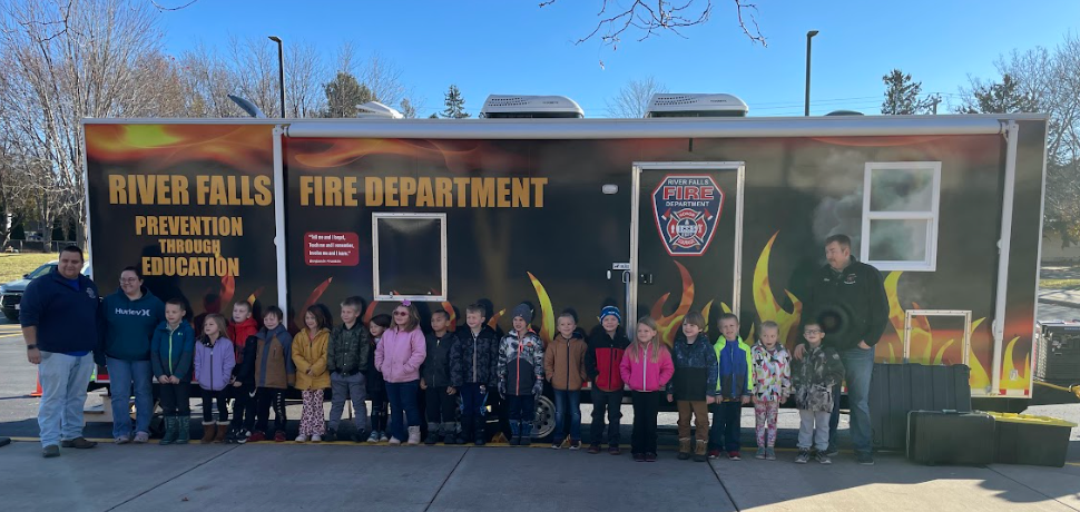 Grade school students standing in line in front of a fire safety truck.