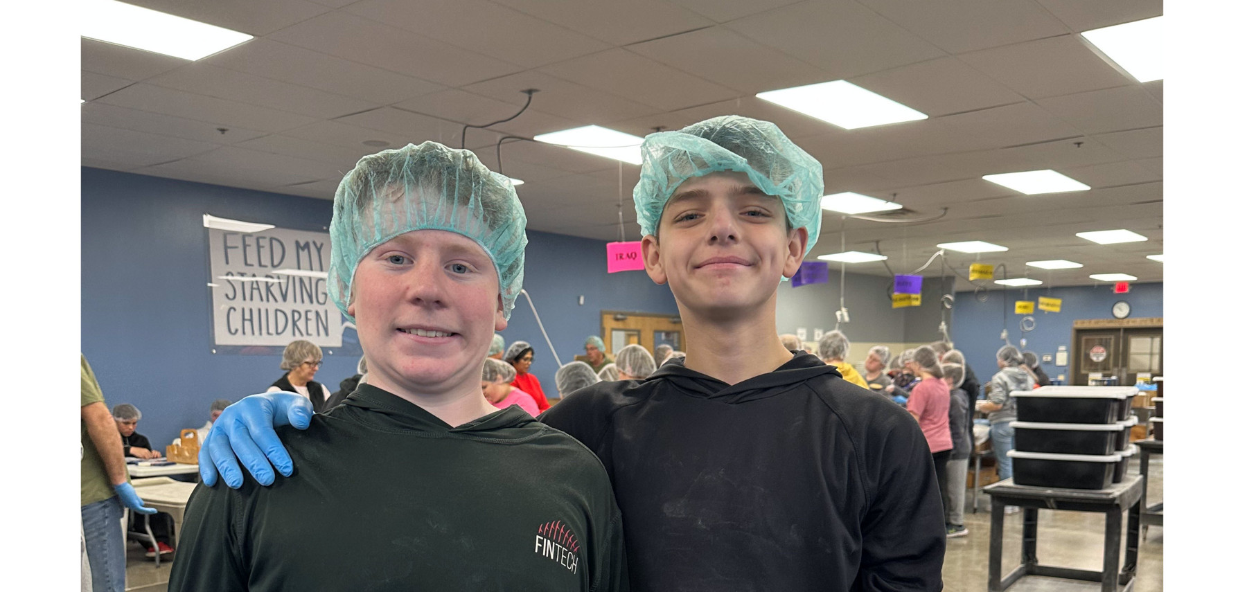 Two students posing with hairnets and gloves at Feed My Starving Children organization.